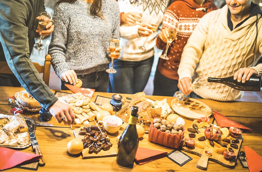 Side view of friends group tasting christmas sweets food and having fun at home drinking champagne sparkling wine - Winter holidays concept with people enjoying time eating together - Warm filter